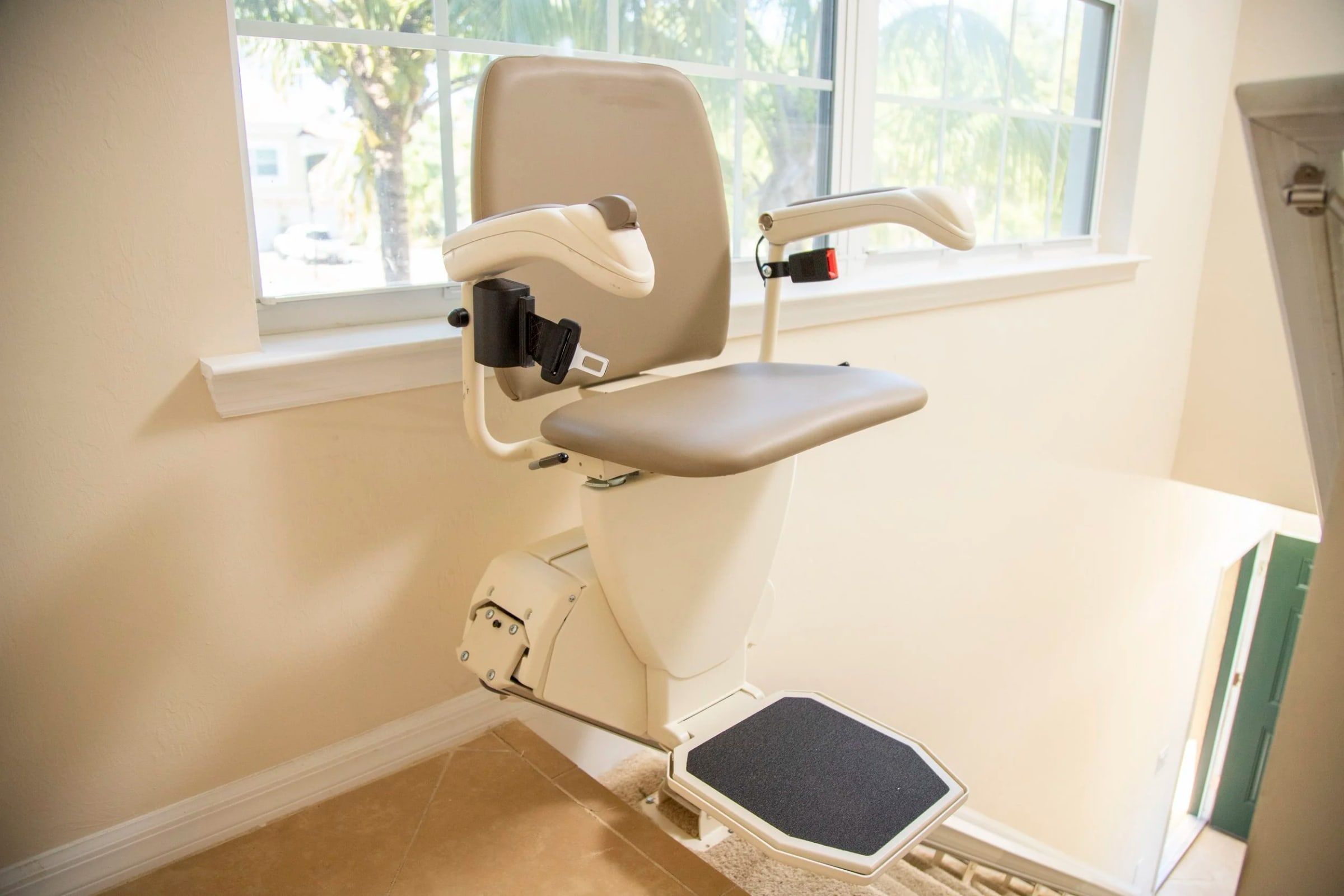 Harmar SL600 stairlift parked at the bottom of carpeted stairs