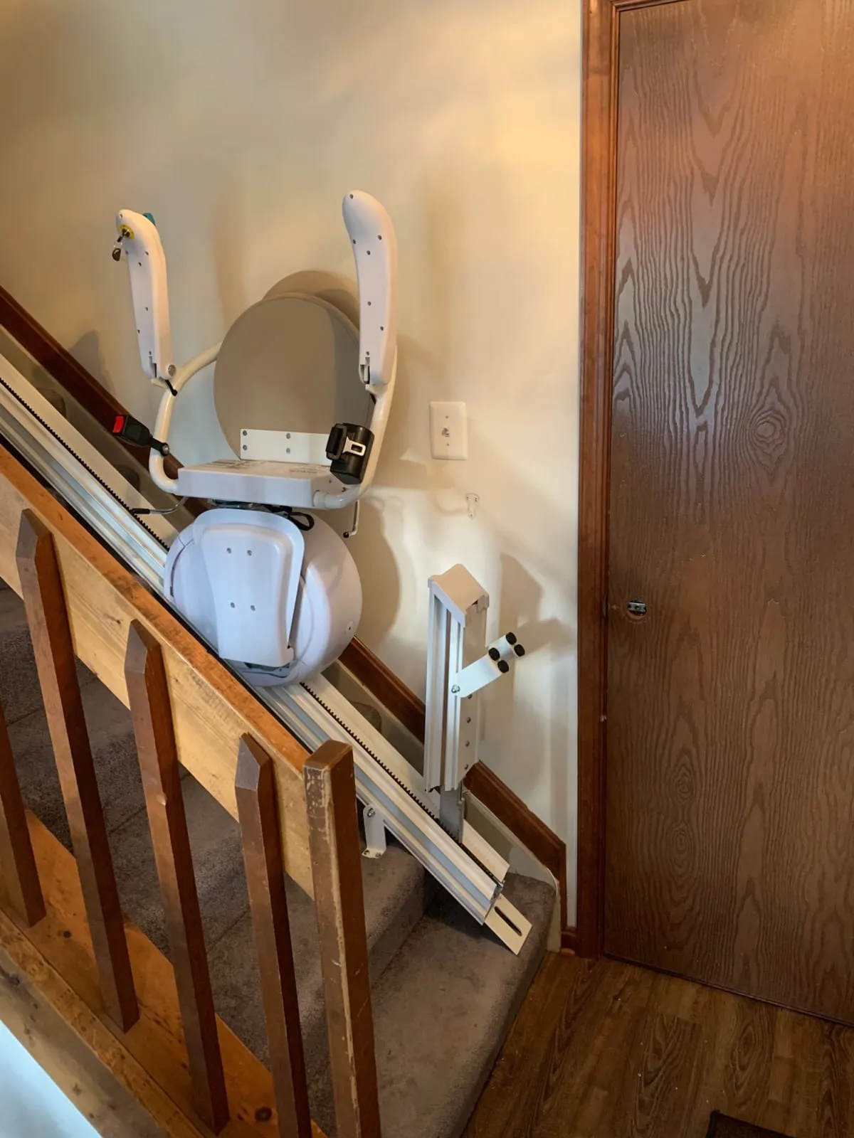 Savaria K2 stairlift folded beside a hardwood staircase