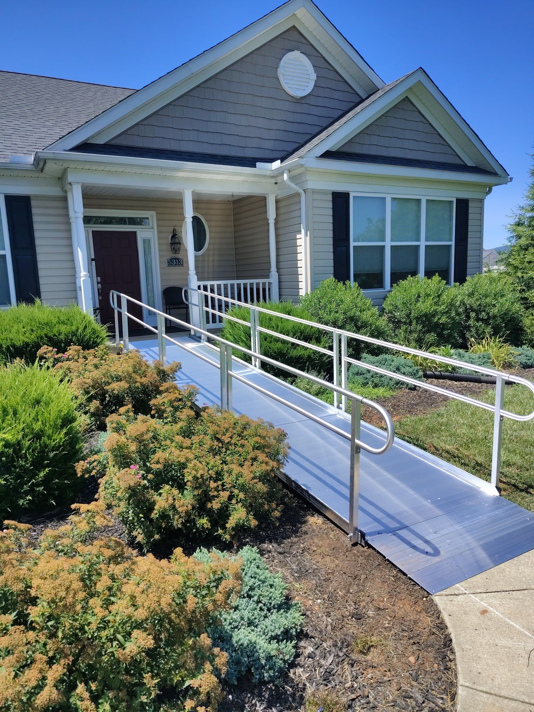Aluminum modular wheelchair ramp with handrails leading to the front door of a home in Frederick, MD