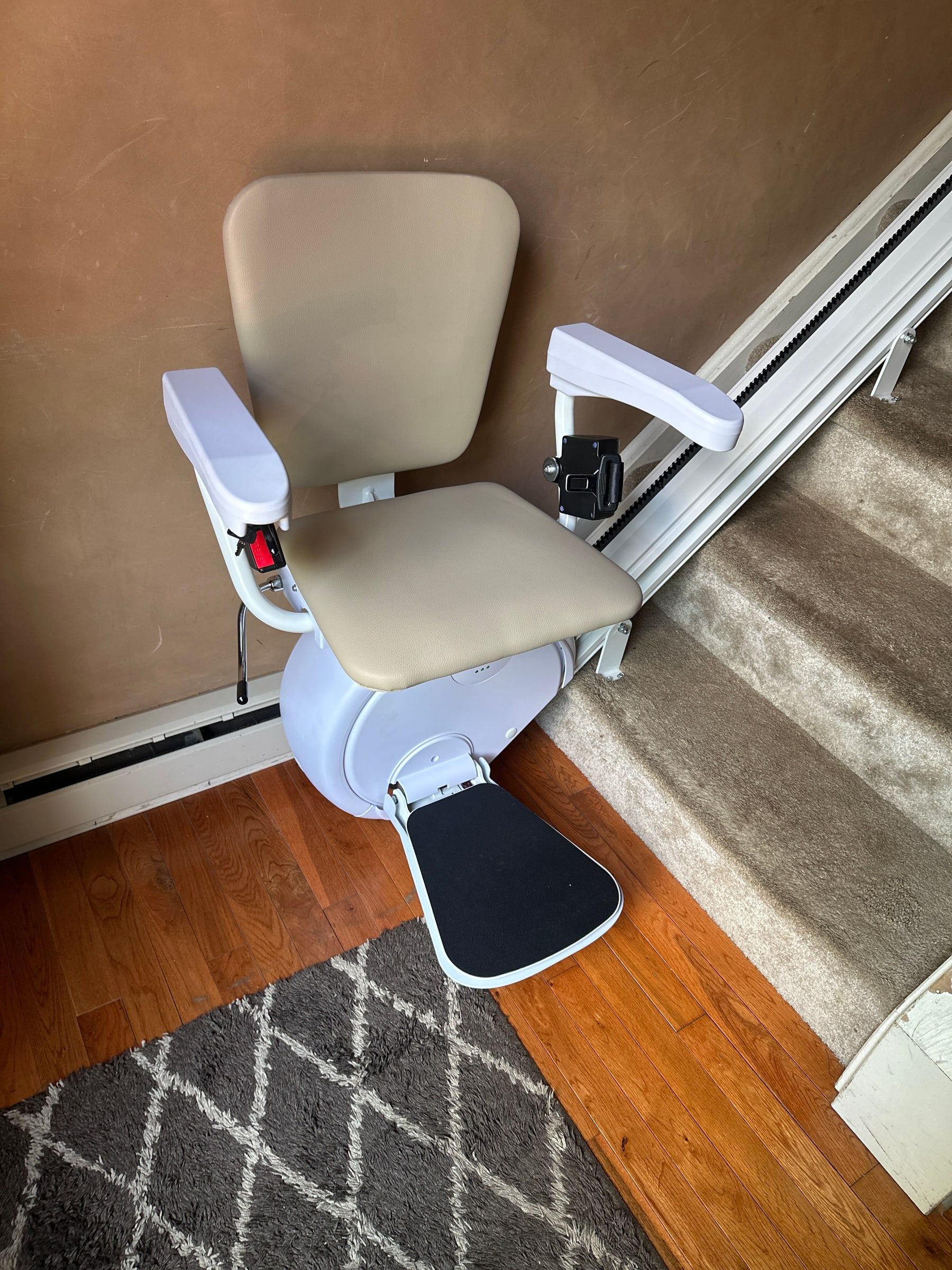 A new straight stairlift installed on a carpeted staircase in a Harrisburg, Pennsylvania home, seat folded down and ready to ride